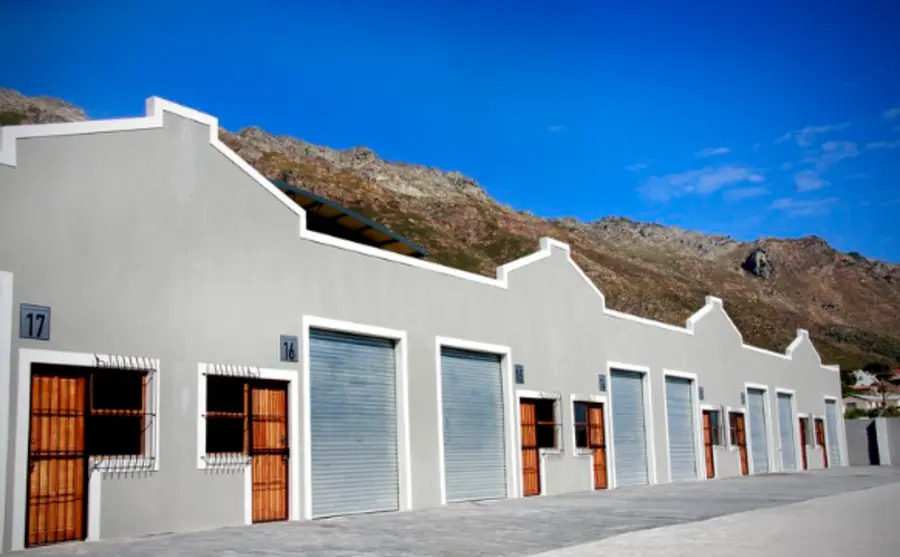 White factory units with roller doors under a blue sky