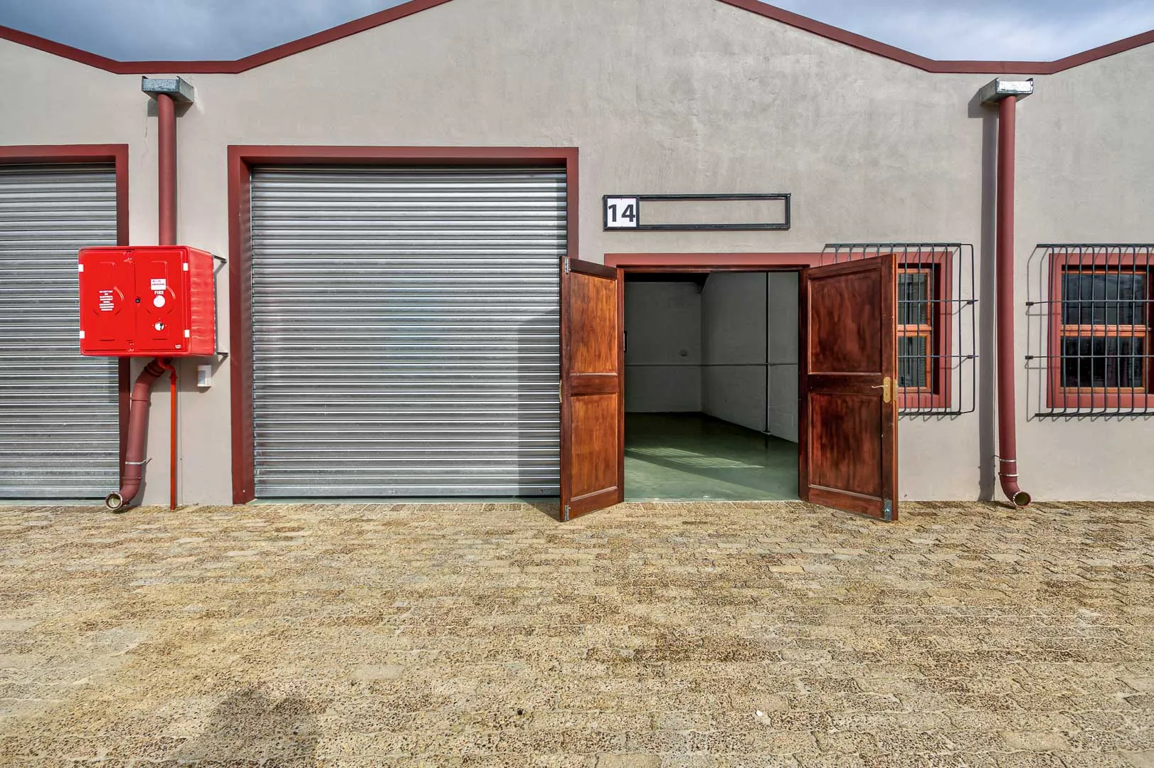Unit 14 with its roller door, open timber doors and a fire hose reel